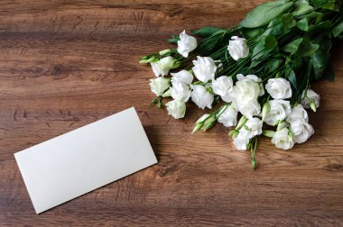 Kart ve ahşap arka planda beyaz Eustoma çiçekleri, klasik renkli.