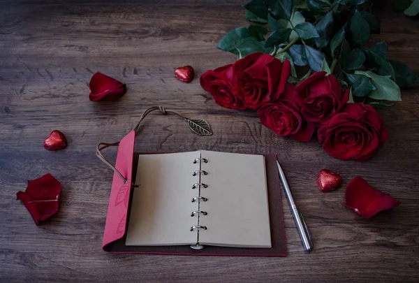 Notebook for writing with a pen and bouquet of red fragrant roses — Stock Photo, Image