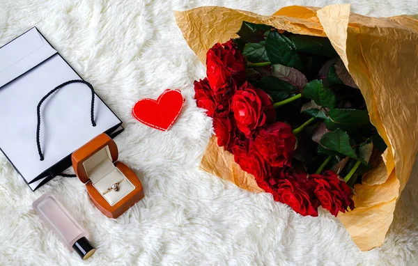 Rose fiori in un bellissimo bouquet, una scatola con un regalo di festa e una bottiglia di profumo — Foto Stock
