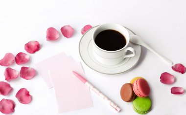 Kahve, makron, kalem ve kağıt bardaklar.