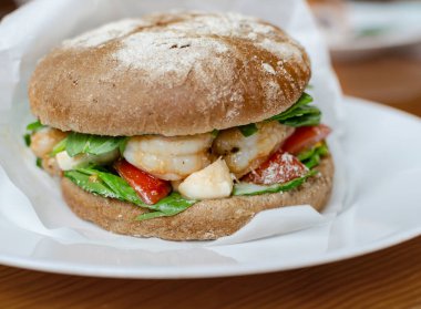 Tahta arka planda sebzeli, siyah unlu karides burger, evde lezzetli yemekler, kapat.