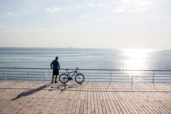 Морской пейзаж человек велосипед наблюдая восход солнца — стоковое фото