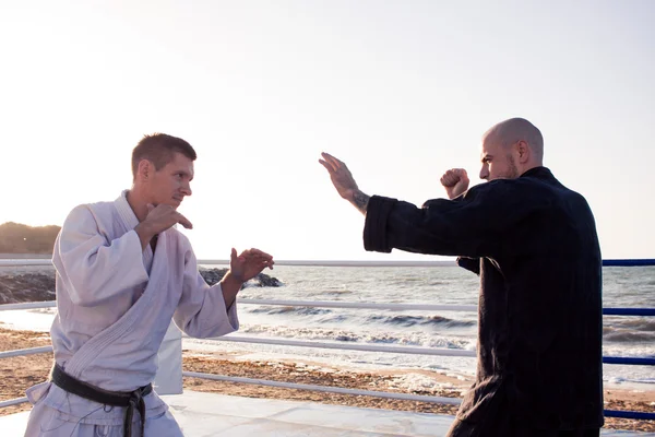 Picture of two karate fighters in morning light practicing martial arts outdoors — Stock Photo, Image