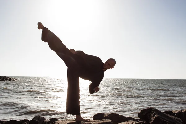 Тренировки каратэ на камнях на морском фоне — стоковое фото