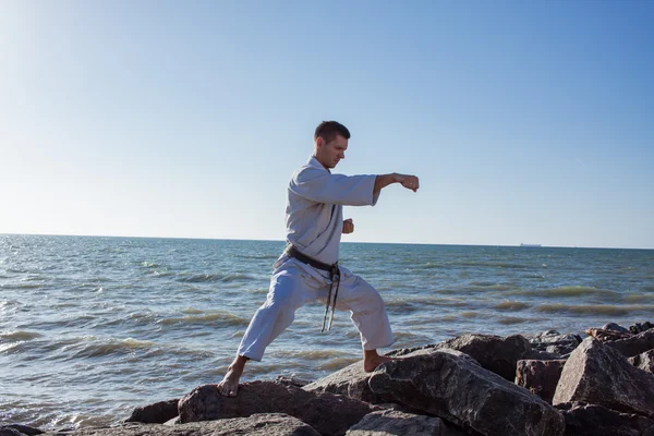 Karate fighter training on stones sea background — Stock Photo, Image