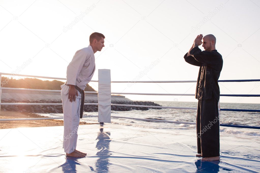   karate fighters are fighting on the beach boxing ring in morning