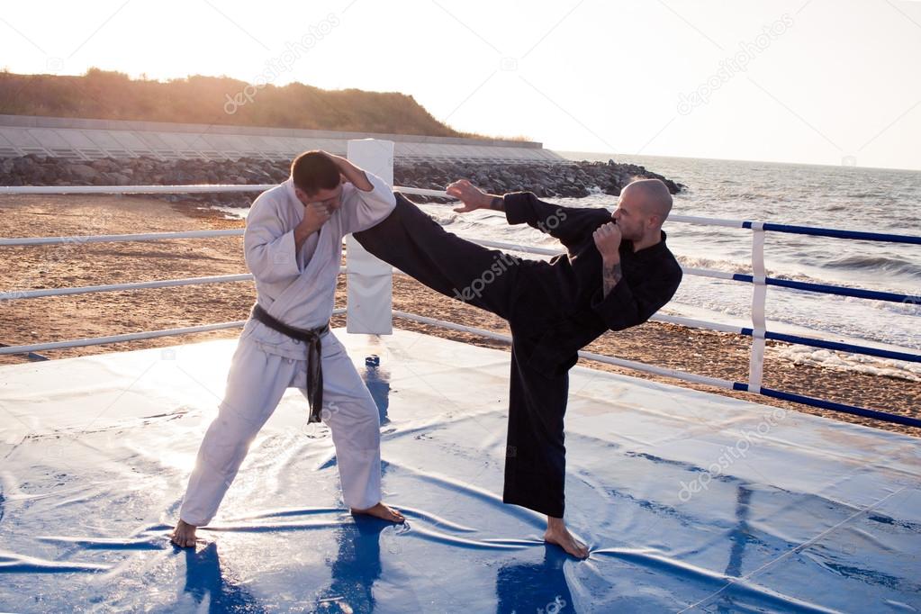 picture of Two professional  karate fighters are fighting on the beach boxing ring 