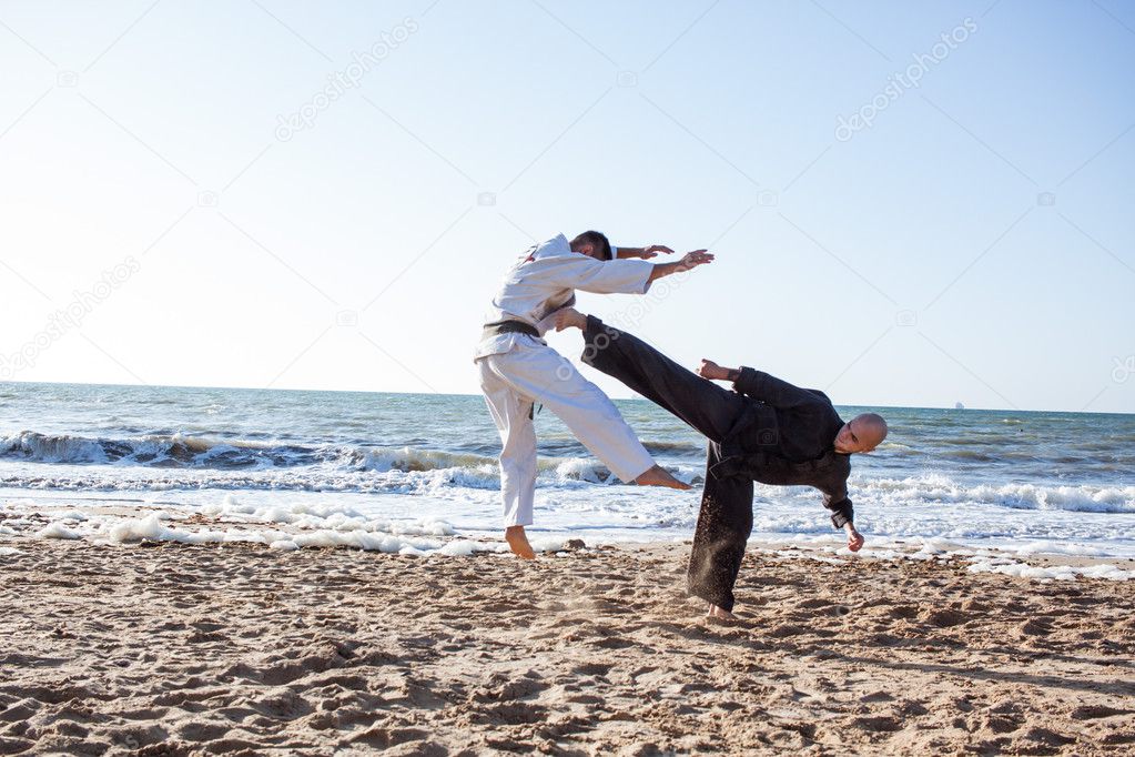 professional karate fighters training on the beach sea background