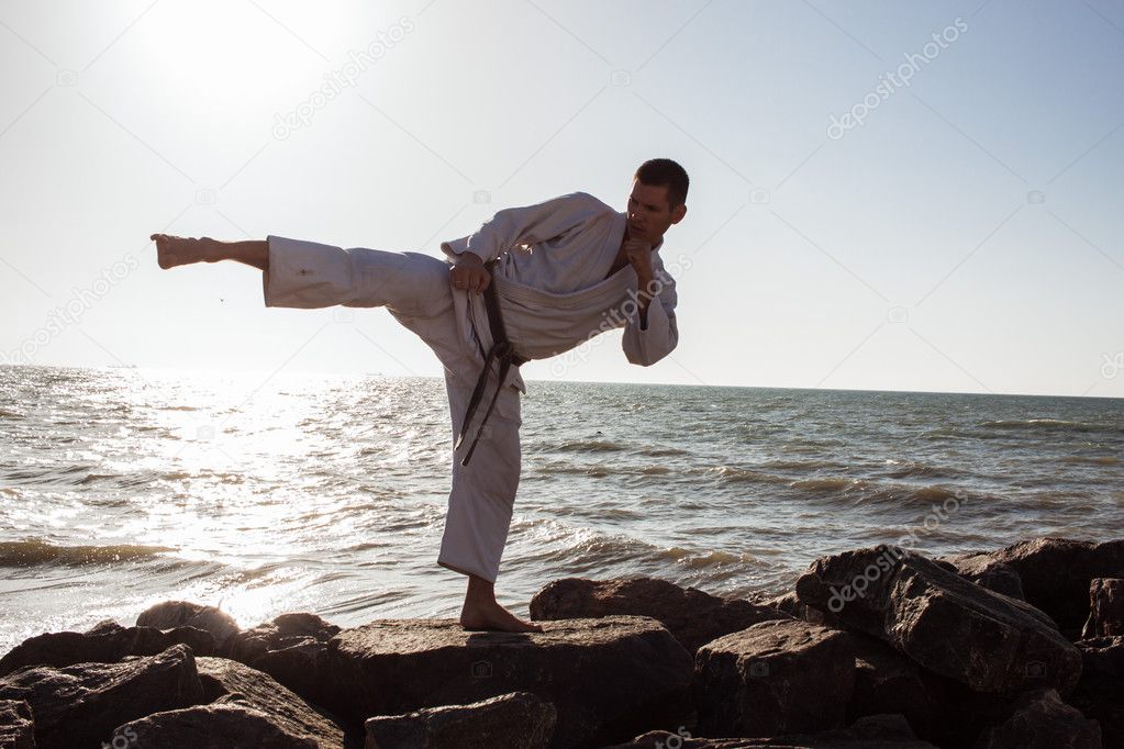 male karate fighter posing on stones sea background