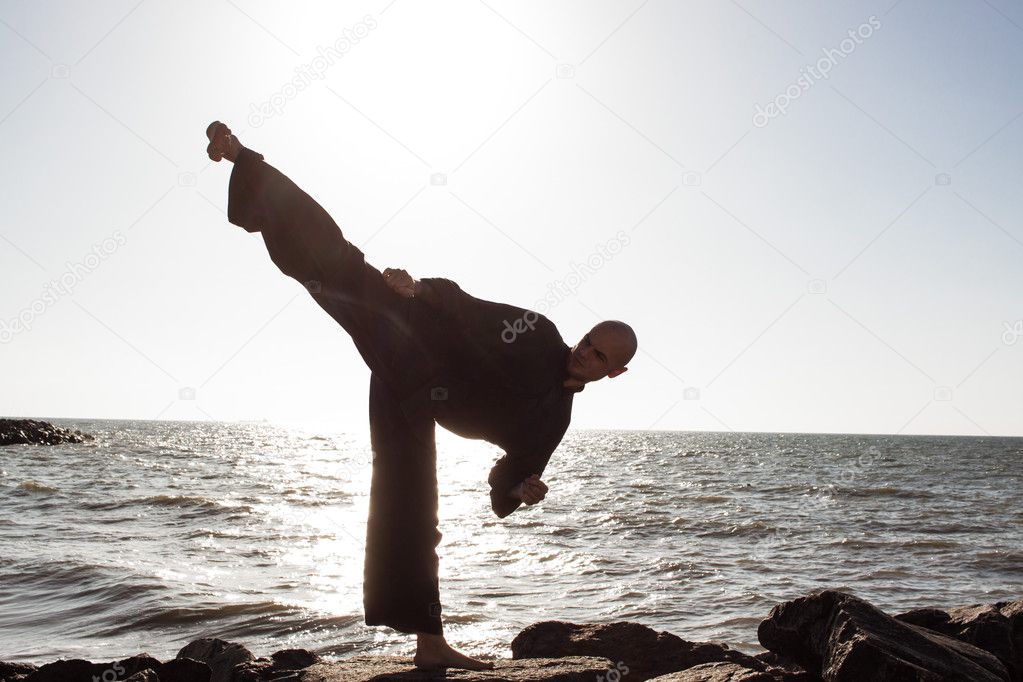 male karate fighter training on stones sea background