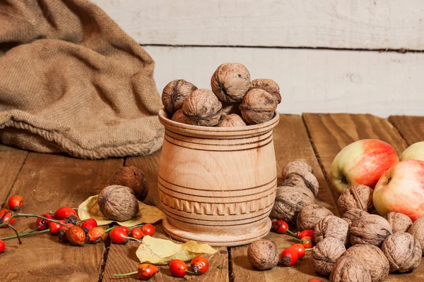 Manzanas y walnat en cesto, briar sobre tabla de madera vieja —  Fotos de Stock