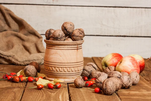 Äpfel und Walnat im Korb, auf altem Holzbrett ländliche Dekoration — kostenloses Stockfoto