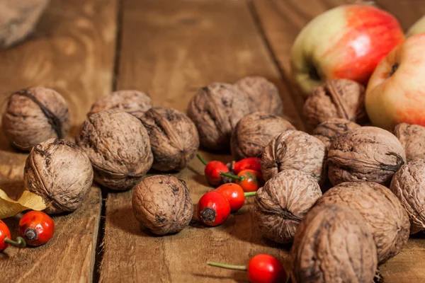 Manzanas y walnat en cesto, briar sobre tabla de madera vieja con otoño le —  Fotos de Stock