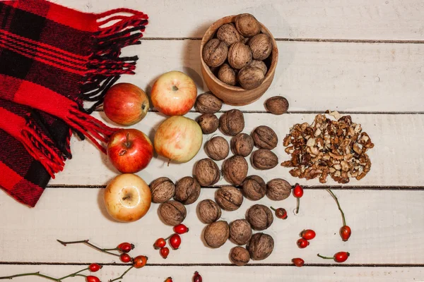 Walnats, briar, apples and scarf on white wooden table — стоковое фото