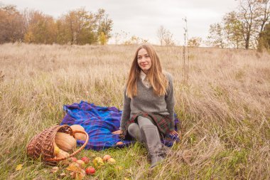 genç ve güzel kadın üzerinde piknik sepeti sonbahar hasat ile vakit geçiriyor