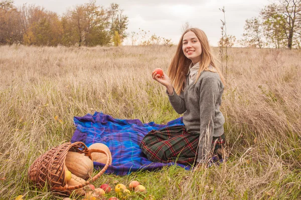 Mladá krásná žena v polích s jablkem v ruce a koš s dýně — Stock fotografie