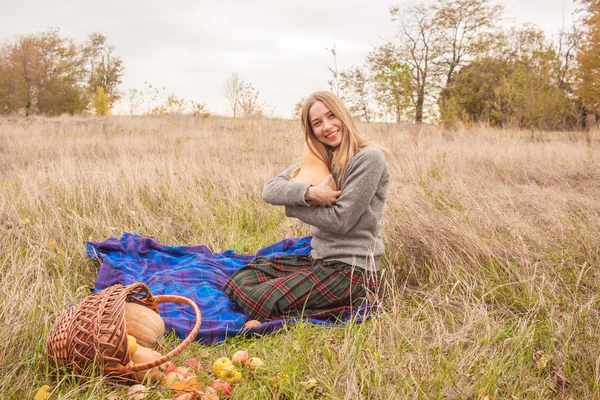 Pique-nique d'automne de jeune femme sur carreaux et panier de pommes — Photo