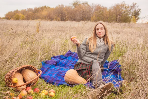 Jolie jeune femme ayant du temps sur pique-nique avec pomme à la main et panier de récolte d'automne — Photo