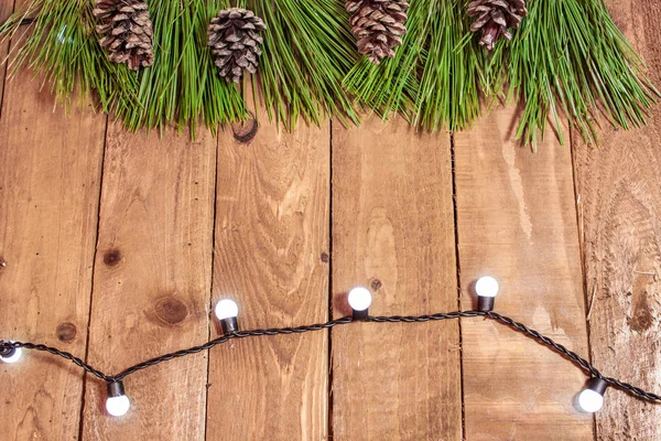 Rama de abeto sobre tabla de madera vieja con fondo de luces — Foto de Stock