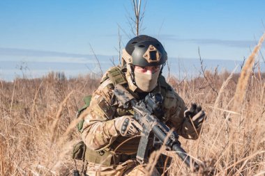 amaçlayan, airsoft oyuncu ile silah, kask ve kurşun geçirmez yelek çalılıkların oturan