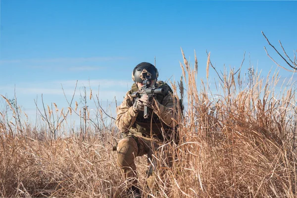 Soldado airsoft com um rifle e amunição completa sentado em arbustos — Fotografia de Stock