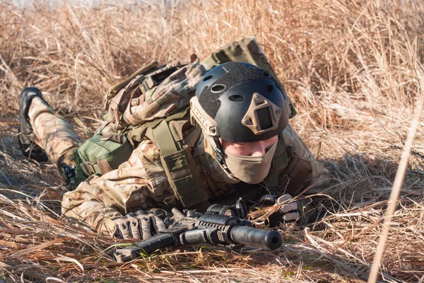 Krypande airsoft soldat med ett gevär i fält — Stockfoto