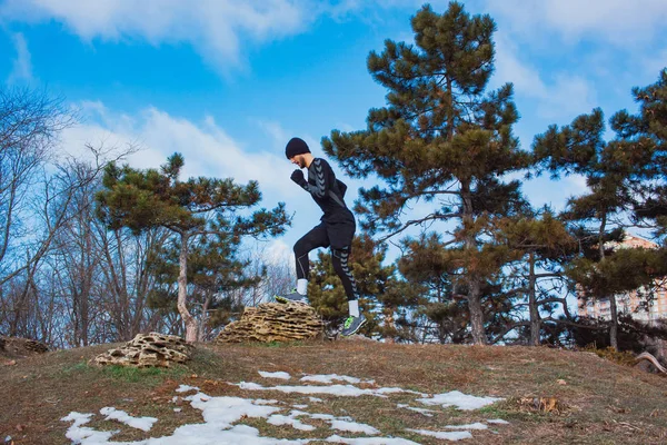Бегун делает упражнения на холме в зимнем парке — стоковое фото