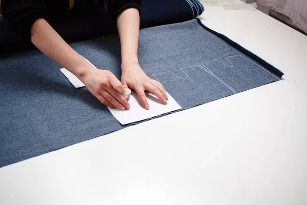 Manos de costurera en la mesa de trabajo con patrón y cinta métrica . —  Fotos de Stock