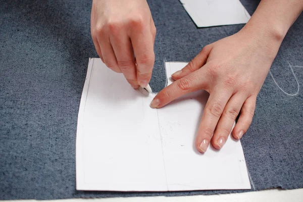 Seamstress hands on the work table with pattern and measuring tape. — Stock Photo, Image