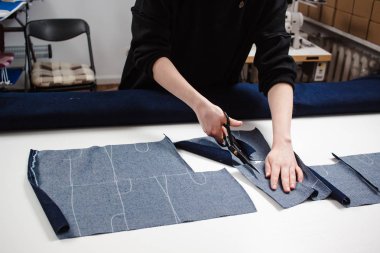 El kot kumaş beyaz masada makasla kesme terzi