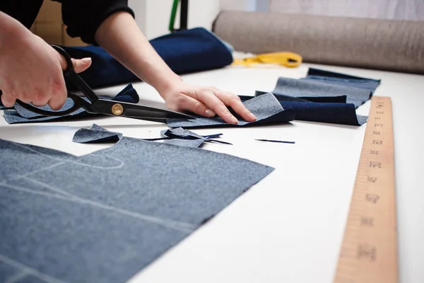 Schneiderin schneidet mit der Schere einen Jeansstoff auf weißem Tisch — Stockfoto