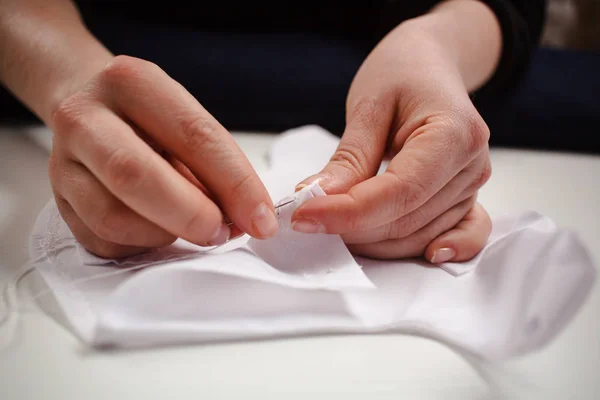 Quadro de close-up das mãos de uma costureira no trabalho com tecido branco — Fotografia de Stock