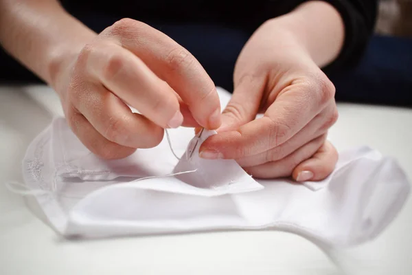 Quadro de close-up das mãos de uma costureira no trabalho com tecido branco — Fotografia de Stock