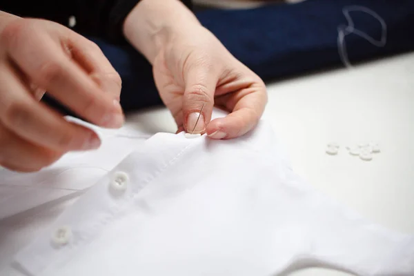 Quadro de close-up das mãos de uma costureira no trabalho com tecido branco — Fotografia de Stock