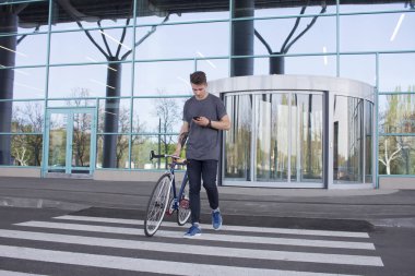  Adam yolda yürürken bir düzenleme bisiklet ile. Genç yenilikçi retro bisiklet üzerinde yaya geçidi, mesaj cep telefonu üzerinde yürüme ile
