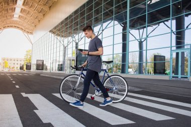  Adam yolda yürürken bir düzenleme bisiklet ile. Genç yenilikçi retro bisiklet üzerinde yaya geçidi, mesaj cep telefonu üzerinde yürüme ile
