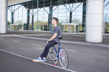 Genç hipster adamla sabit vites bisiklet şehir sokak üzerinde. büyük ayna windows arka plan 