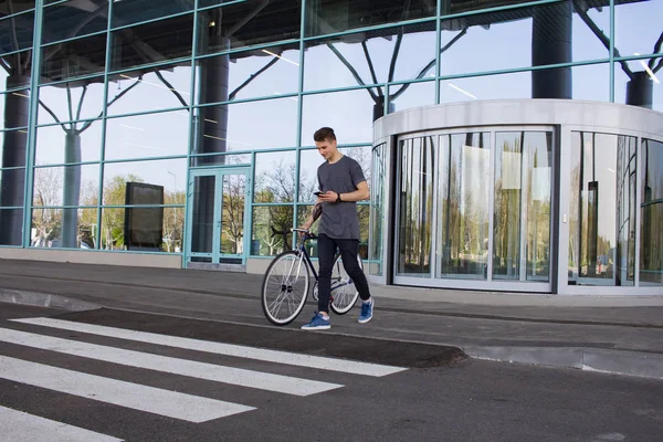 Muž s fixie kole na silnici. mladí bokovky s retro kolo, které chůzi na přechod pro chodce a textových zpráv na mobil — Stock fotografie