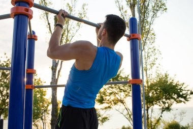 Kaslı adam pull-up yatay bar, diktatör park açık jimnastiği eğitim sabah üzerinde yapıyor. 