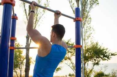 Kaslı adam pull-up yatay bar, diktatör park açık jimnastiği eğitim sabah üzerinde yapıyor. 