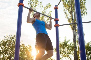 Kaslı adam pull-up yatay bar, diktatör park açık jimnastiği eğitim sabah üzerinde yapıyor. 