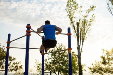 Kaslı adam pull-up yatay bar, diktatör park açık jimnastiği eğitim sabah üzerinde yapıyor. 