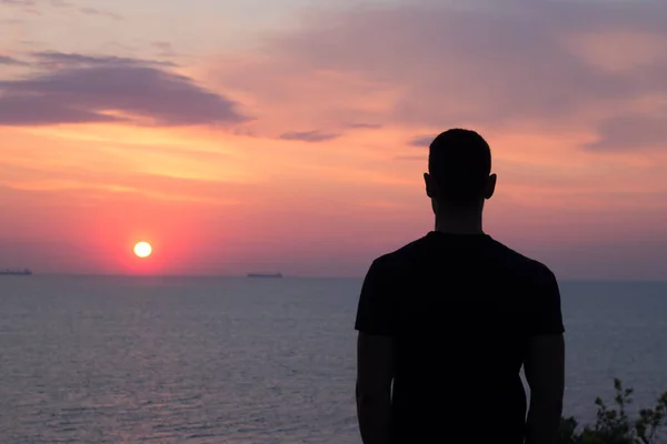 Silhouette alkalmas fiatal ember néz wunset vagy napfelkeltét a tenger, vagy óceán — Stock Fotó