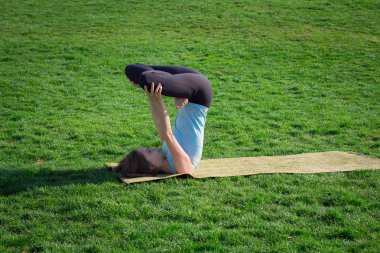 genç güzel kadın doeing yoga asans yoga mat ile yeşil çimlerin üzerine yerleştirmek