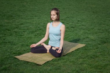 genç güzel kadın doeing yoga asans yoga mat ile yeşil çimlerin üzerine yerleştirmek