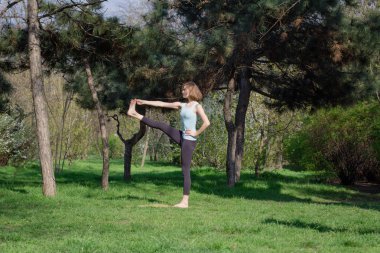 Genç kadının yaz Şehir Parkı yoga egzersizleri yapması.