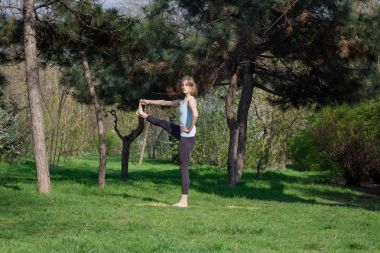 Genç kadının yaz Şehir Parkı yoga egzersizleri yapması.