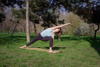 genç güzel kadın doeing yoga asans pines Park yoga mat ile yerleştirmek