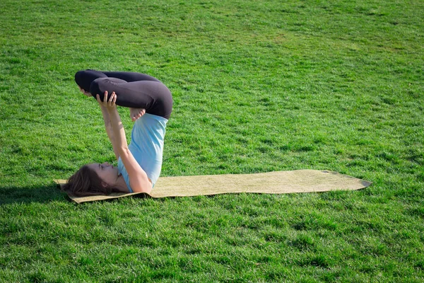 Joven hermosa mujer en forma haciendo yoga asans en la hierba verde con estera de yoga — Foto de Stock
