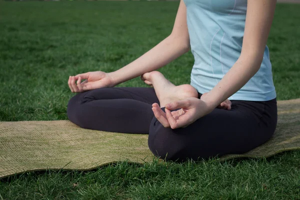 Mooie jonge past vrouw doeing yoga asans op het groene gras met yoga mat — Gratis stockfoto